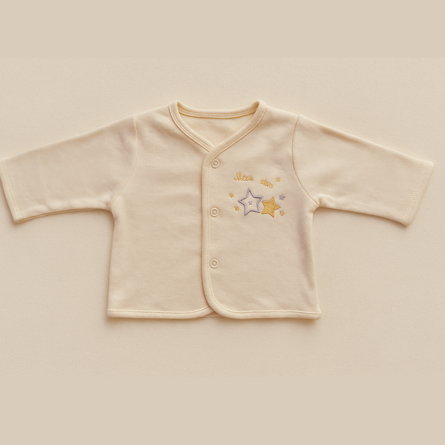 pale yellow baby jacket with star design on a beige background
