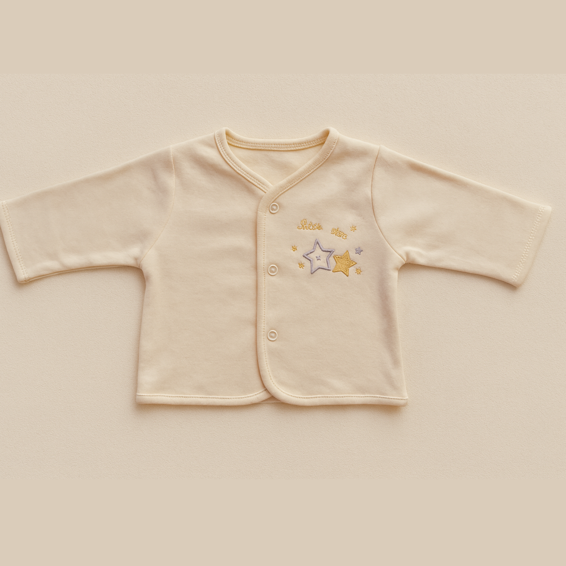 pale yellow baby jacket with star design on a beige background
