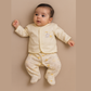 Baby wearing a pale yellow outfit with star and cloud patterns on a beige background