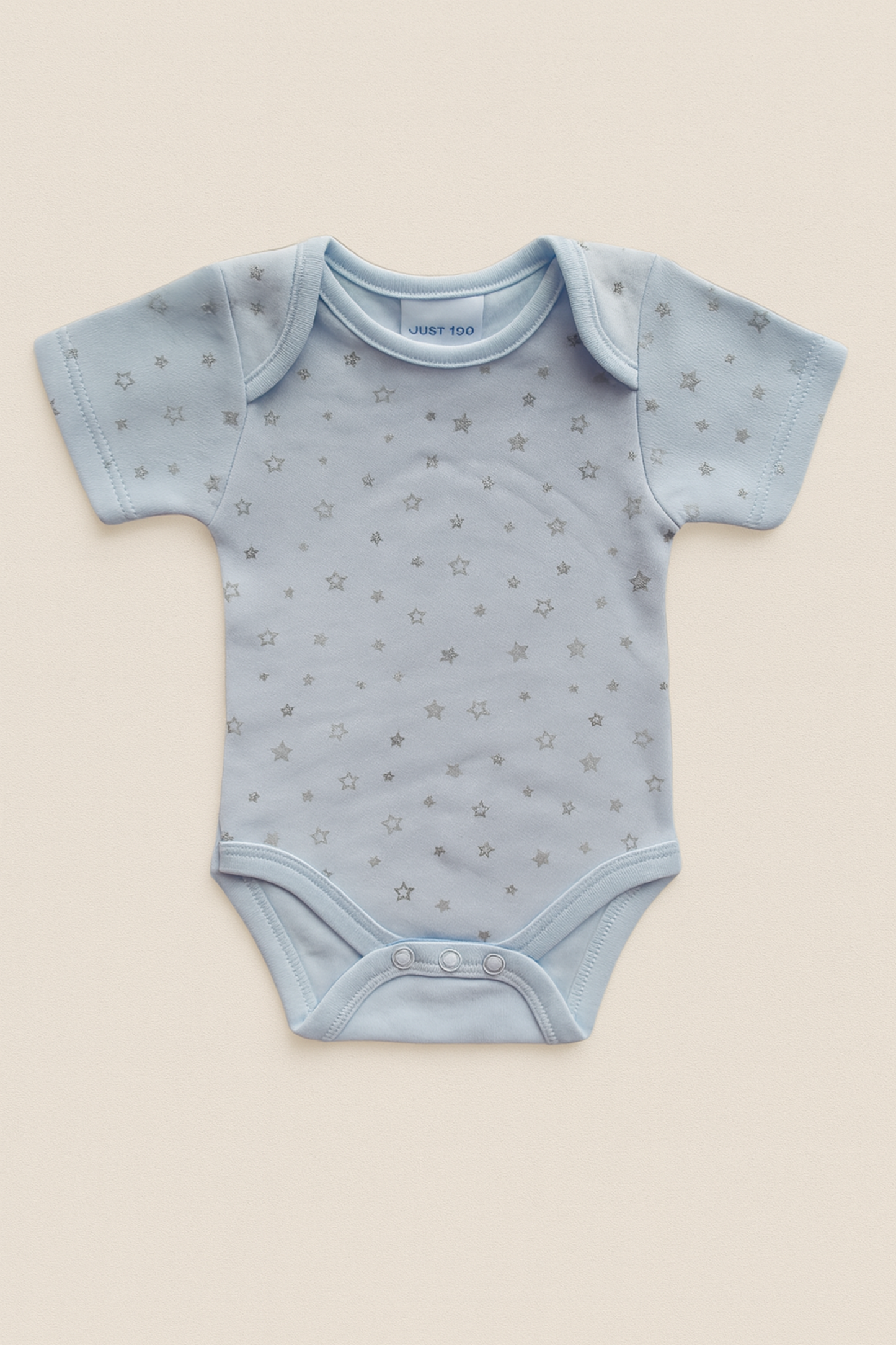 Light blue baby onesie with star pattern on a beige background