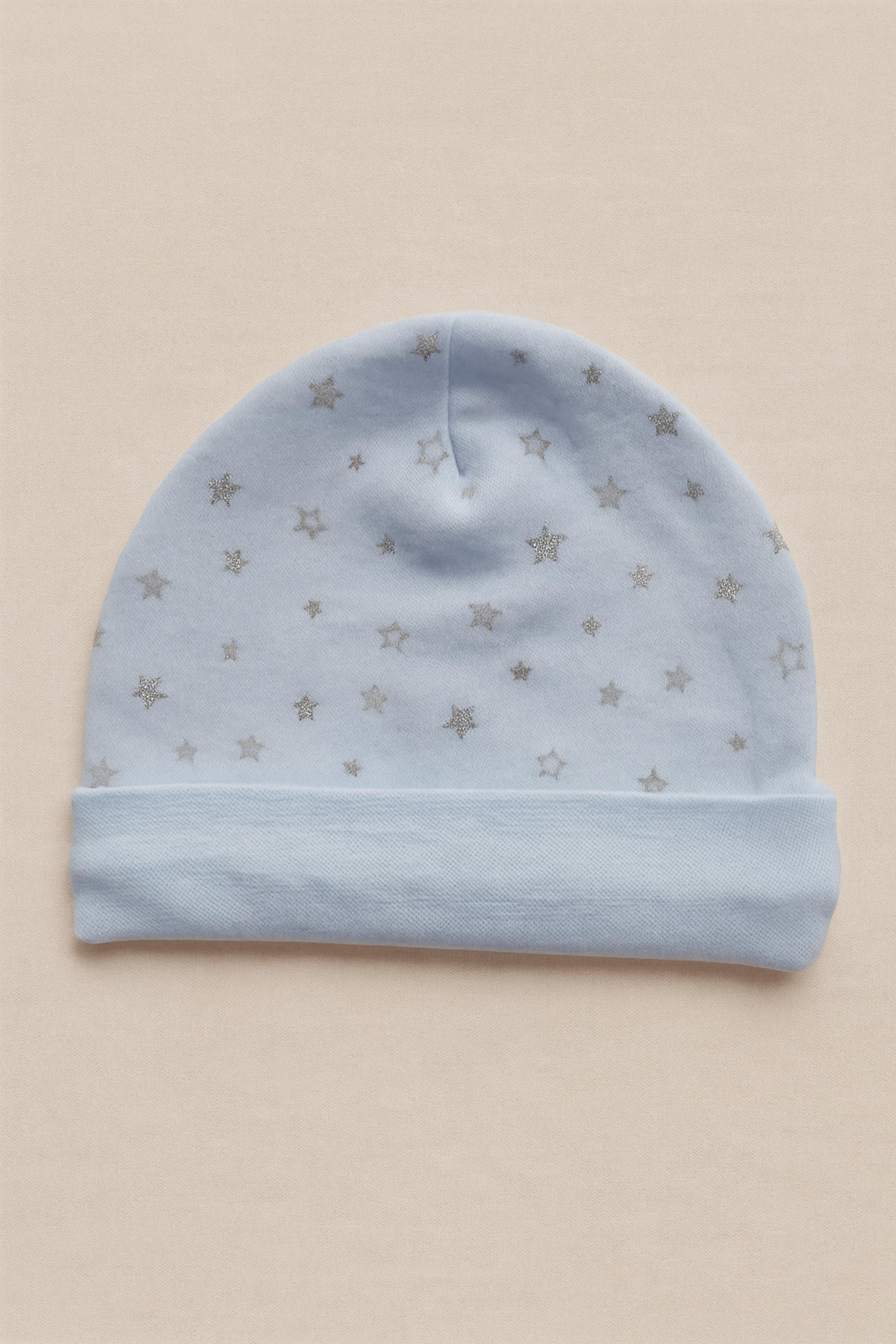 Blue baby hat with star patterns on a beige background