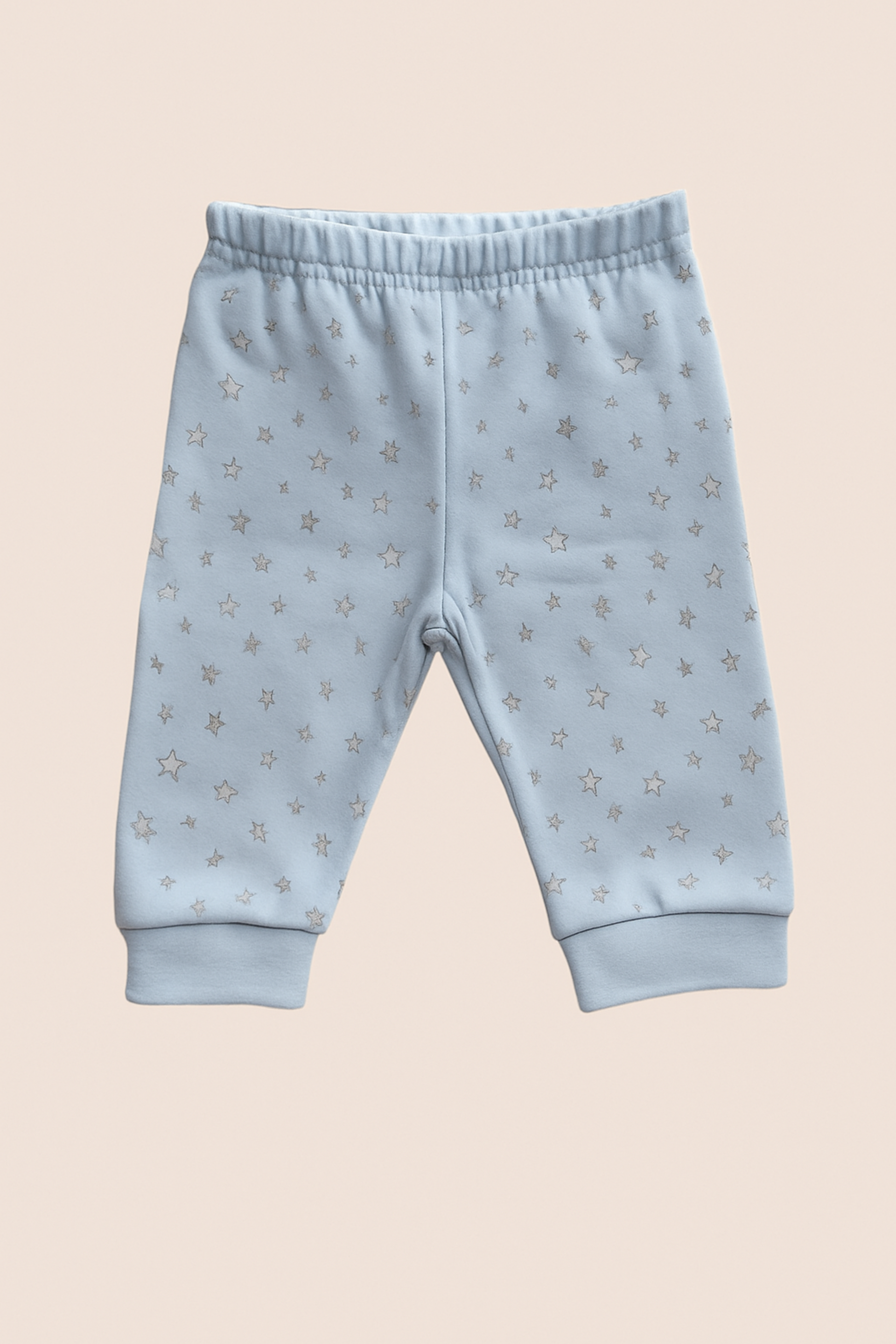 Light blue baby trousers with star pattern on a beige background