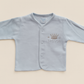 Light blue baby cardigan with 'Prince' and crown embroidery on a beige background