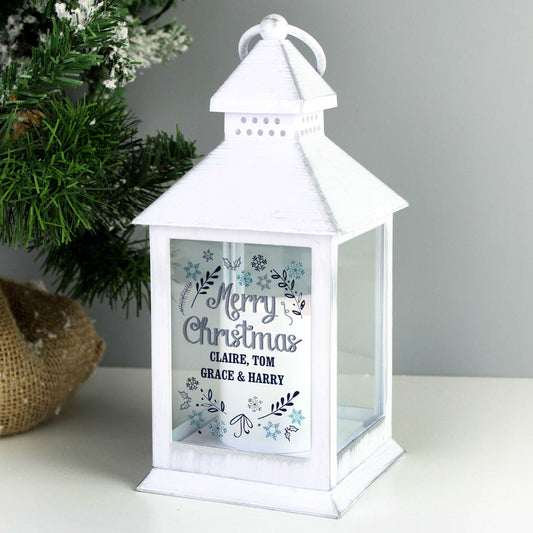 white lantern with christmas design in blue and teal printed on the front pictured on a white surface next to a small Christmas tree By Sweetlea Gifts