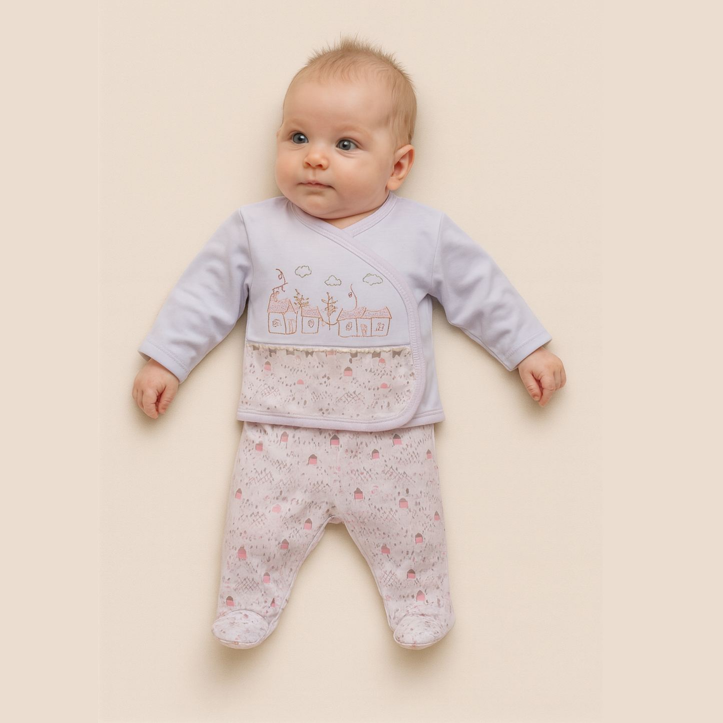 Baby wearing a light pink and white outfit with a pattern on a beige background