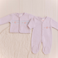 pink baby outfit with embroidered crowns on a light wooden background