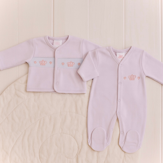 pink baby outfit with embroidered crowns on a light wooden background
