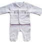 A white baby babygrow and smocked jacket set with a bear motif and paw print detail.