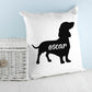 White cushion with silhouette of Dachshund dog with name personalised pictured next to a white wicker basket and pale blue background with white wood floor By Sweetlea Gifts